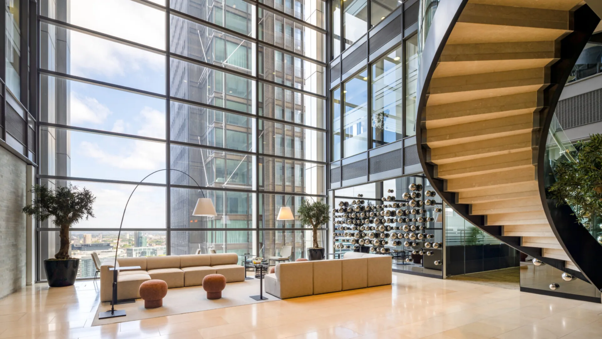 Glass-walled atrium at an Elementa workspace, with a wood spiral staircase and city views